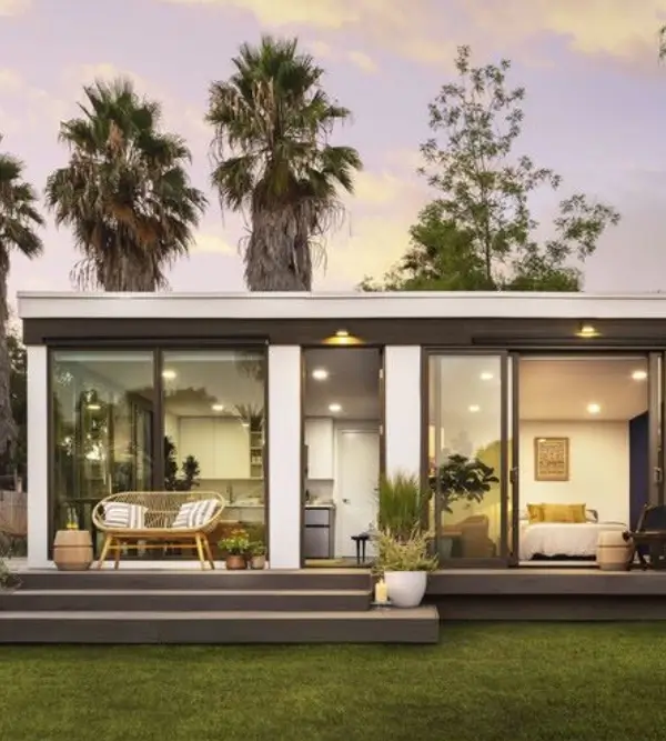 Modern, compact tiny house with large glass windows and outdoor seating area