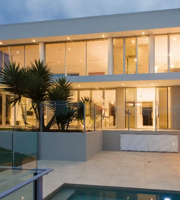 Modern beachfront house with floor-to-ceiling windows and palm trees