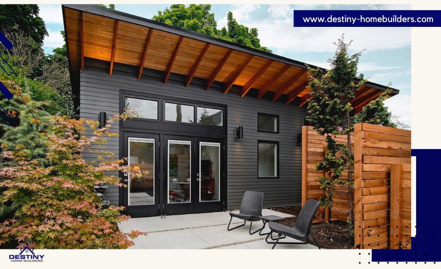 Modern, detached home with gray siding, wood accents, and patio seating