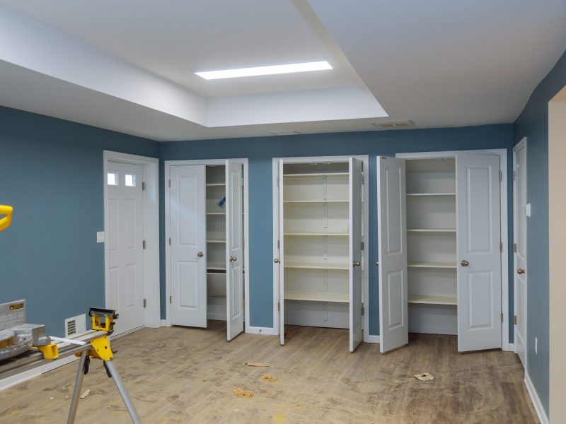 Finishing work in a new home cutting circular saw and nailing wood shoe molding, construction building industry